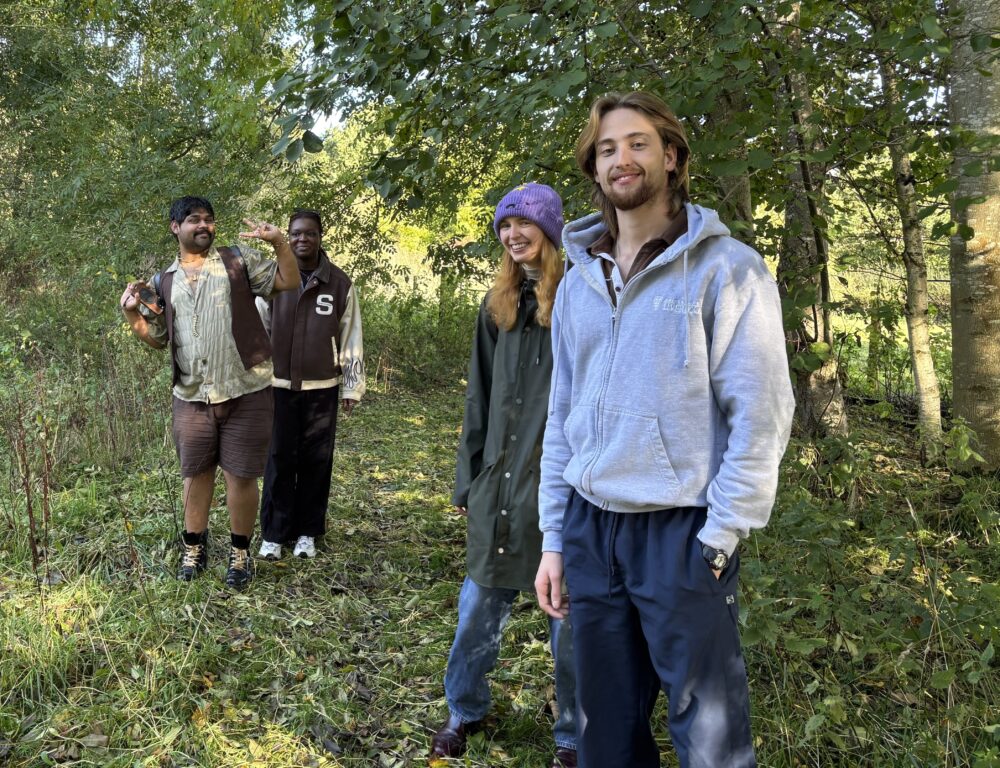 4 young people walking through woods.
