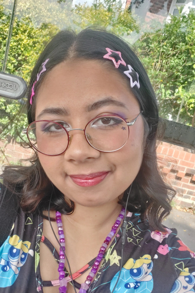 A woman with shoulder length brown hair, glasses looking at the camera smiling