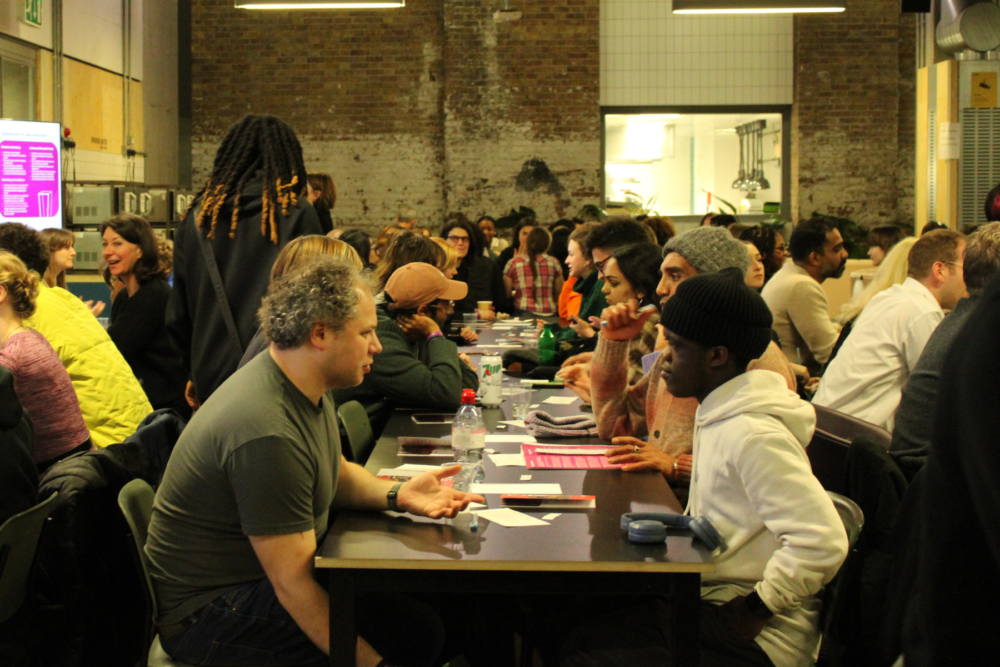 A room with people of varying ages and ethnicities talking to each other across tables.
