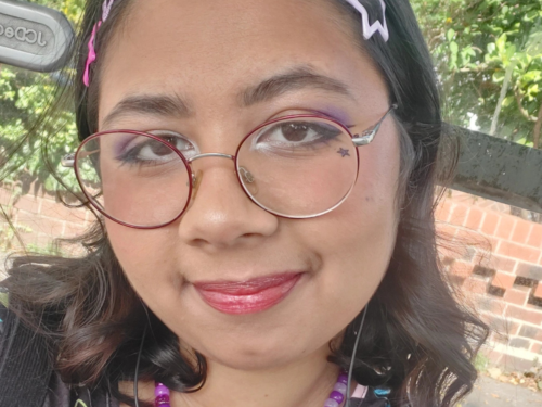 A woman with shoulder length brown hair, glasses looking at the camera smiling