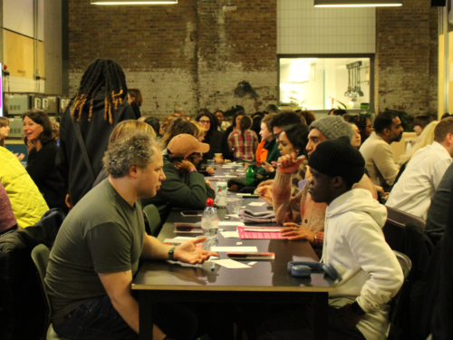 A room with people of varying ages and ethnicities talking to each other across tables.