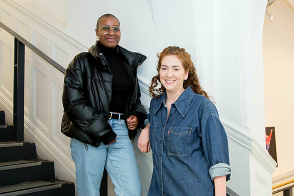 A mentoring pair stand next to each other smiling.
