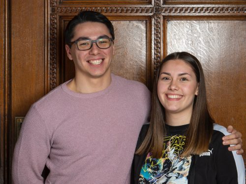 A mentor stands with his arm around his mentee's shoulder