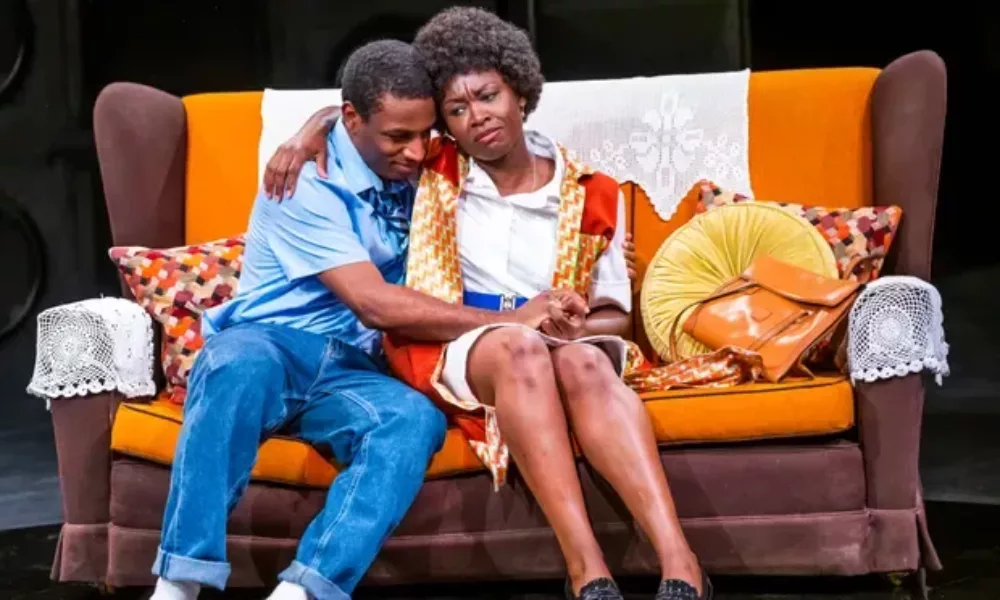 A young person and an older person sitting on a sofa. The older person has their arm round the younger person.
