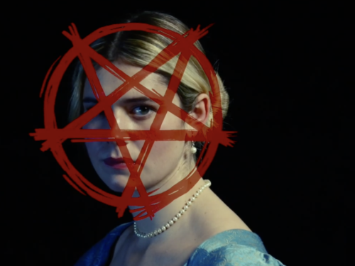 A woman with blonde hair and a blue dress looking serious. There is a red circle with a star over her face.