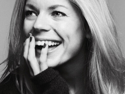 A black and white headshot of a white woman with long blonde hair laughing