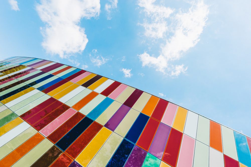 An upwards shot of a building with bright cladding on a sunny day.