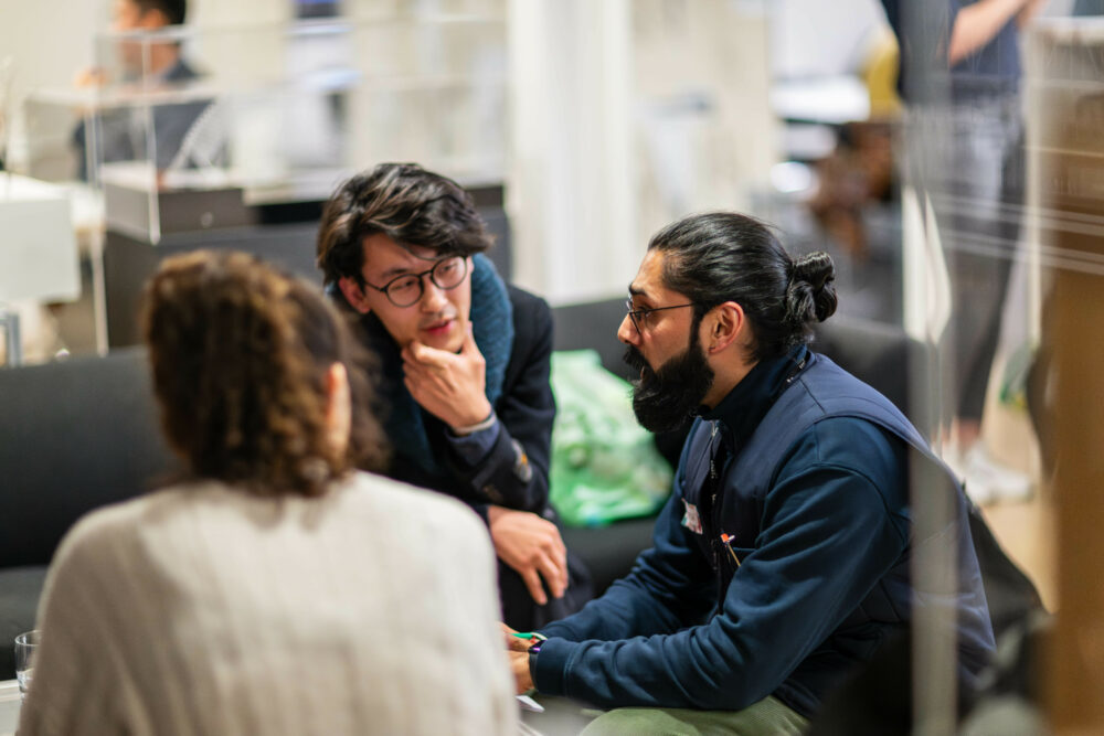 3 people conversing round a table