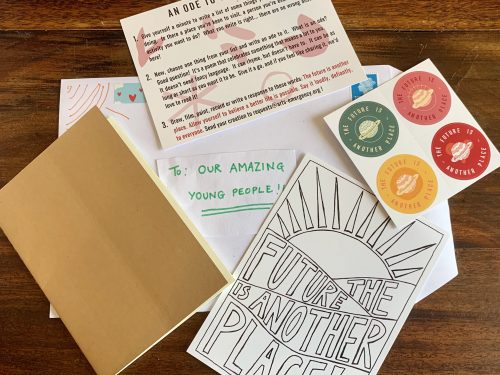 A selection of postcards, stickers and notebook on a wooden surface. An envelope reads to our amazing young people.