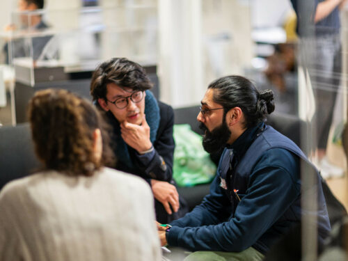 3 people conversing round a table
