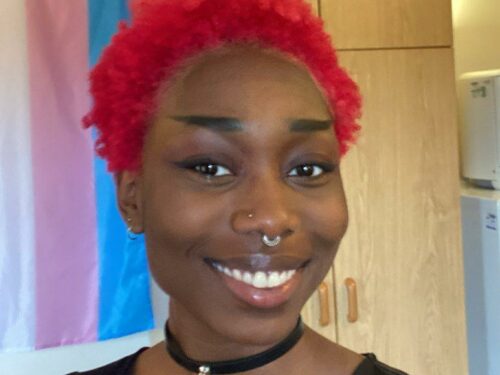 A person with short red hair smiling
