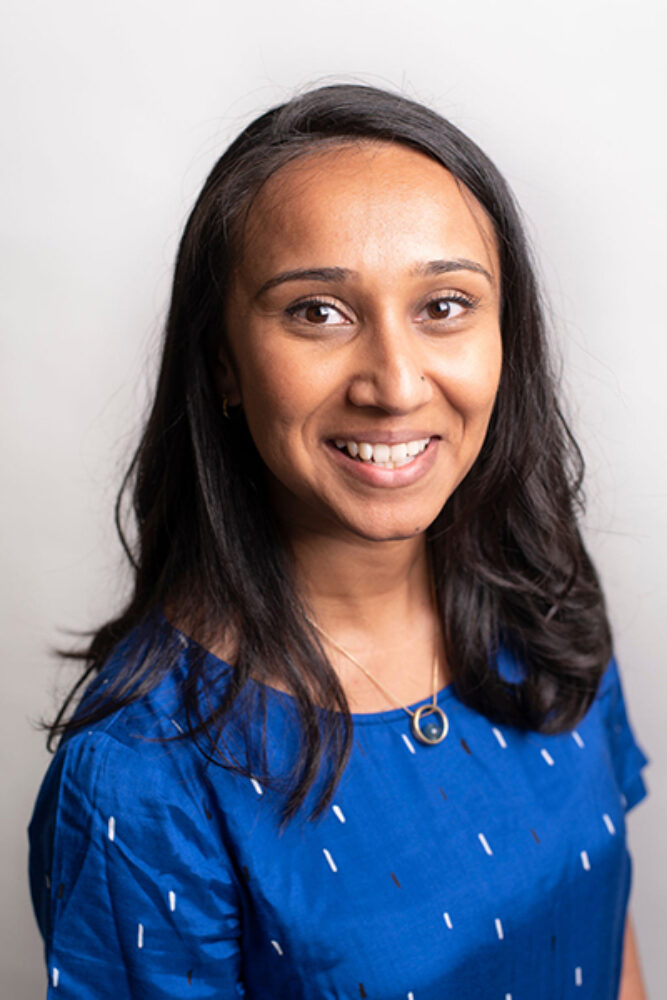 A head and shoulders view of a woman with shoulder length black hair and a blue top