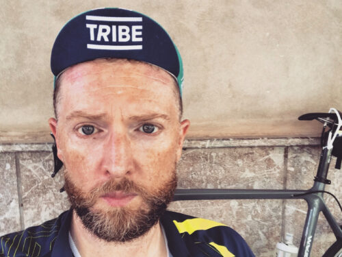A man in a cycling cap looks serious in front of his bike.