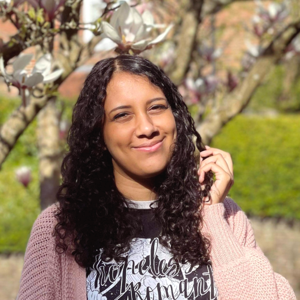 A person with long, brown, curly hair smiling