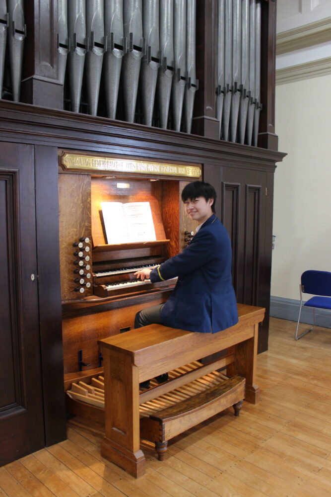 A 17 year-old sat at an organ in Liverpool Cathedral smiling