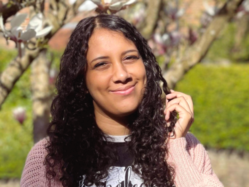 A person with long, brown, curly hair smiling