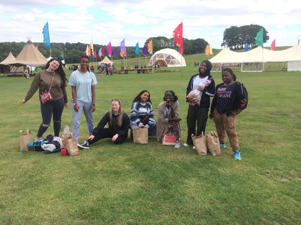 Seven young people standing in a festival field.