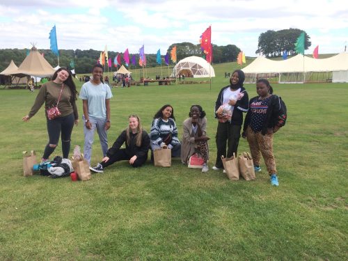 Seven young people standing in a festival field.